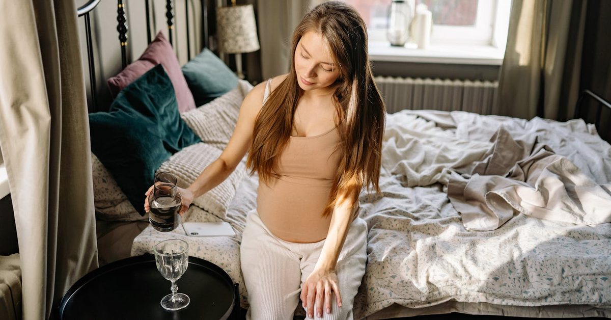 Gestante de 27 semanas em momento de calma sentada na cama