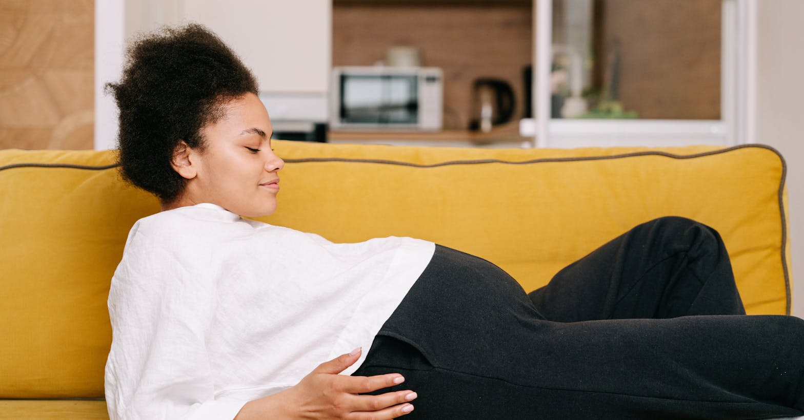 Gestante de 34 semanas descansando no sofá observando a barriga