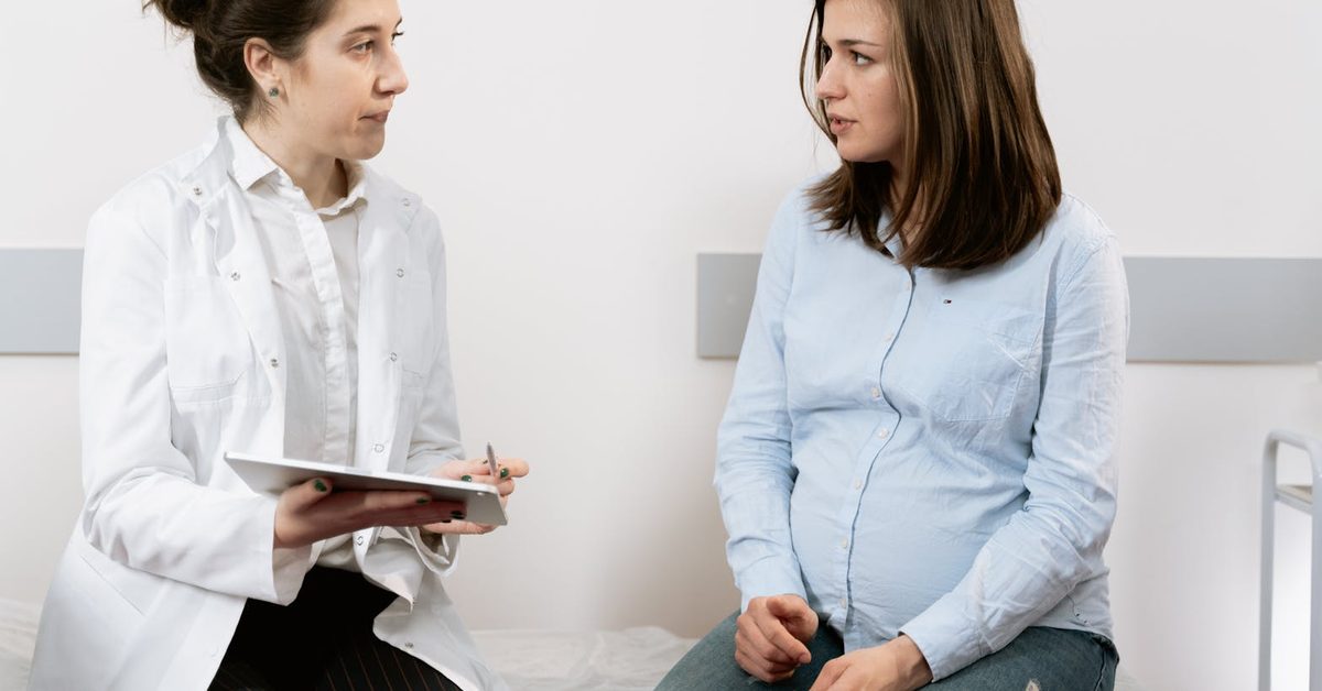 Médica registrando dados na caderneta da gestante durante consulta