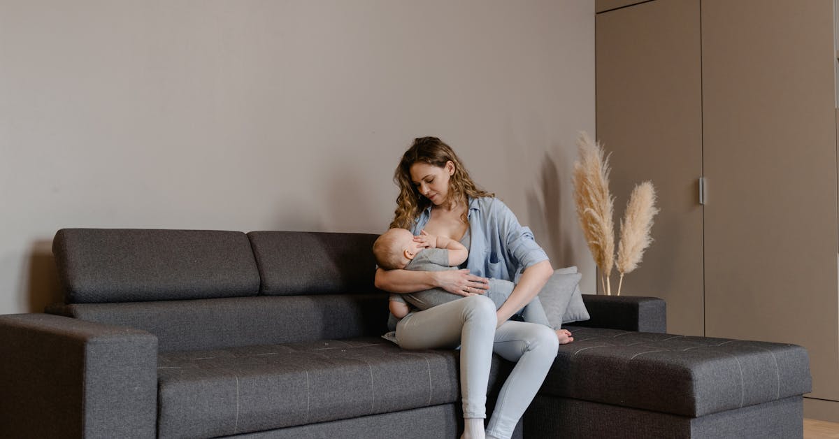 Mãe e bebê em momento de amamentação no sofá